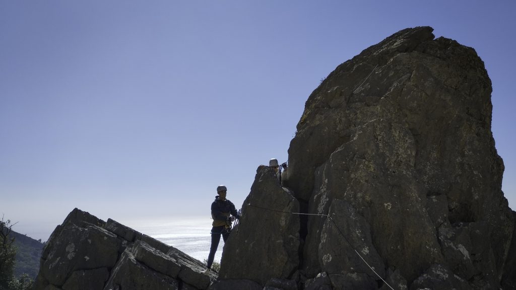 Hiker climbing a metal via ferrata ladder in the Asterousia Mountains.