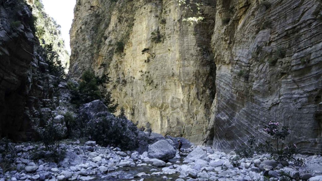 Hikers follow the path of the Tarraios River, crossing refreshing mountain springs and stone riverbeds.