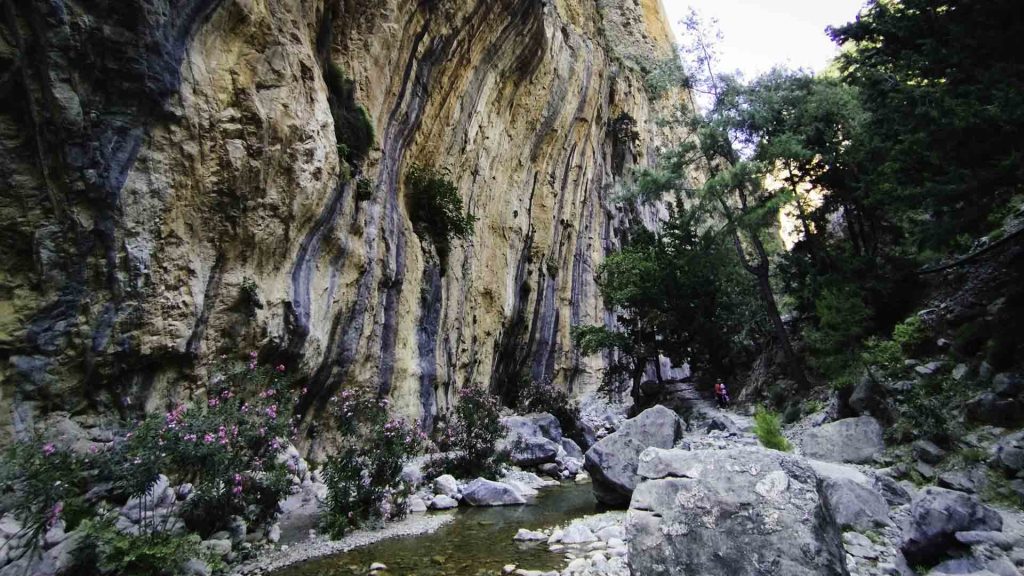 Hikers follow the path of the Tarraios River, crossing refreshing mountain springs and stone riverbeds.