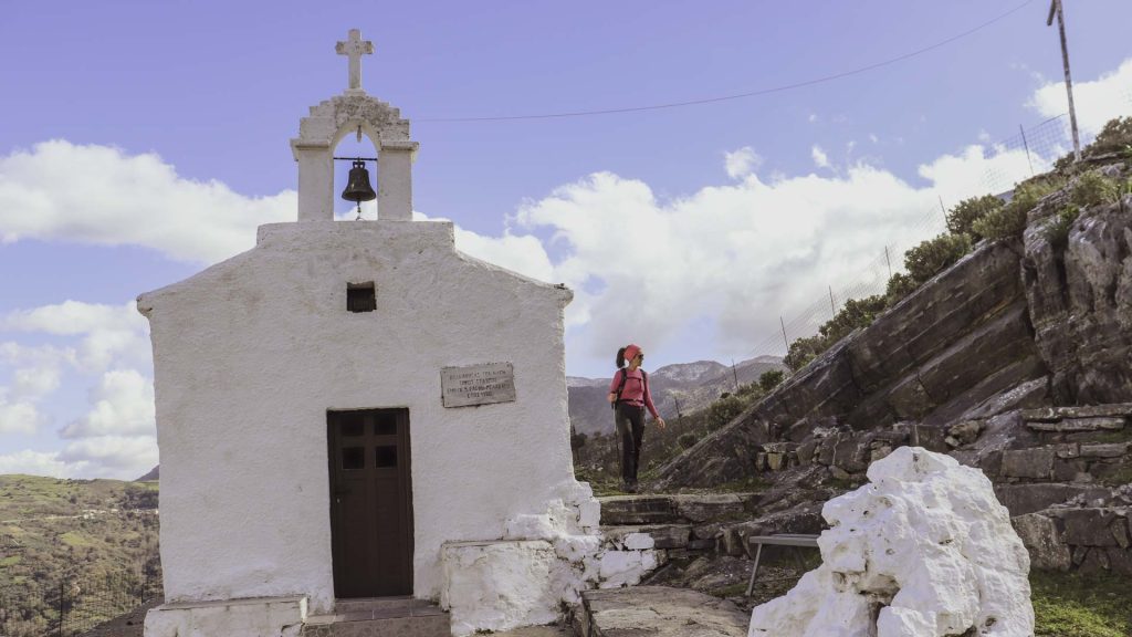 A hiker crossing a chapel on the countryside of Crete as she is moving on the Chania trails network